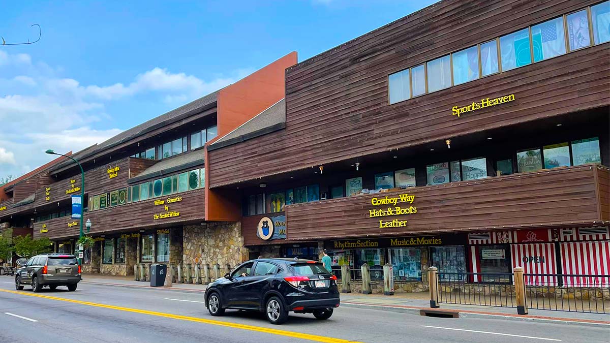 a mall's exterior shot taken at an angle, showing both the street and cars in it
